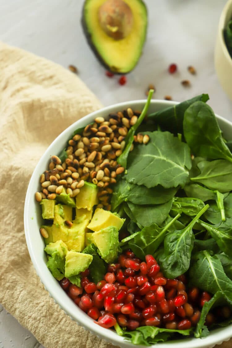 Healthy greens team up with mandarins, pine nuts, avocado, pomegranate seeds, and yummy dressing in this delicious salad!