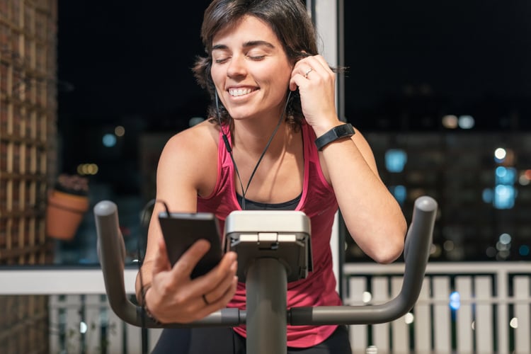 woman listening to music on stationary bike